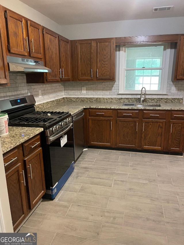 kitchen with light stone counters, stainless steel appliances, light hardwood / wood-style floors, sink, and decorative backsplash