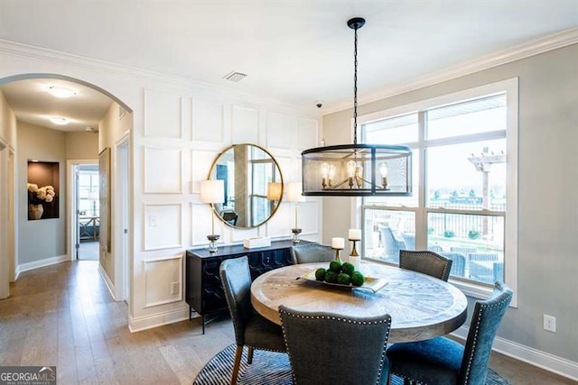 dining area with an inviting chandelier, ornamental molding, and hardwood / wood-style flooring