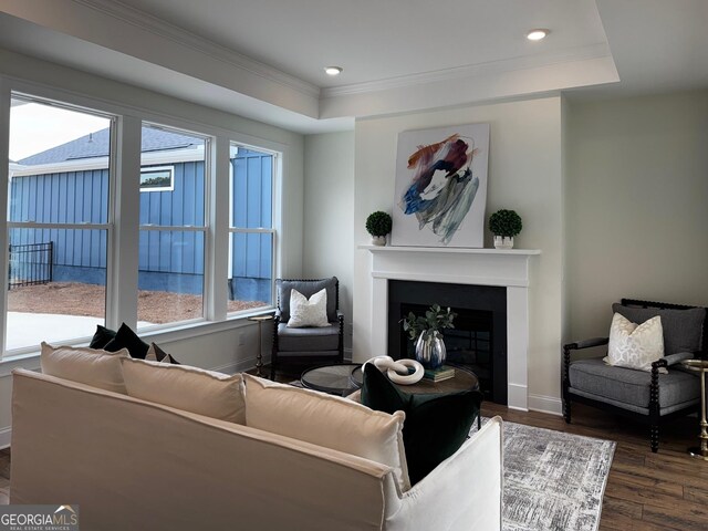 living room with a tile fireplace, plenty of natural light, and crown molding