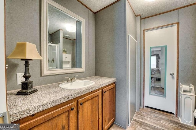 bathroom with crown molding, vanity, hardwood / wood-style floors, and a textured ceiling