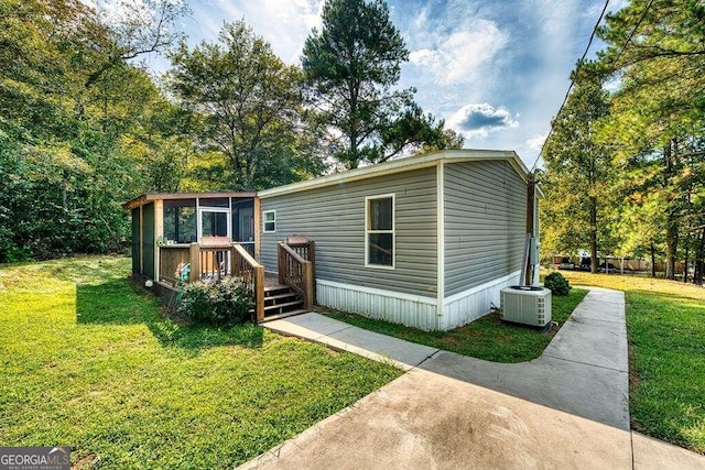 manufactured / mobile home featuring cooling unit, a deck, and a front yard