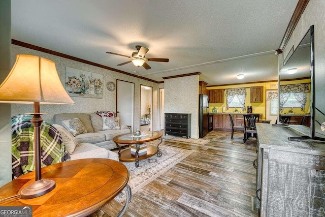 living room with a textured ceiling, ceiling fan, ornamental molding, and hardwood / wood-style flooring