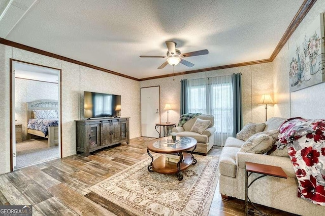 living room with a textured ceiling, ceiling fan, ornamental molding, and hardwood / wood-style floors