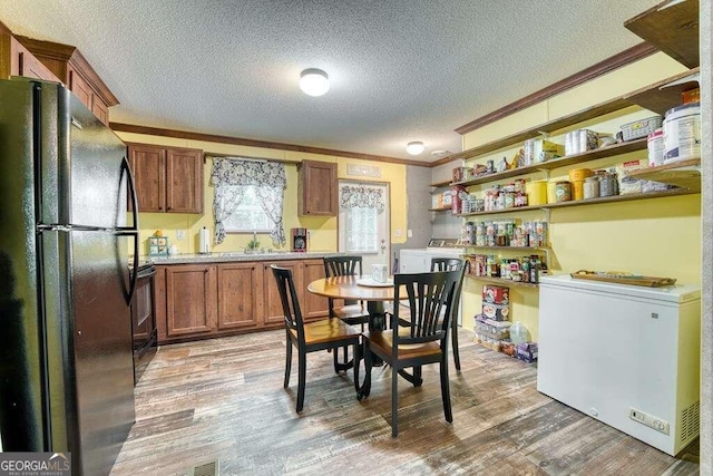 kitchen featuring crown molding, black appliances, wood-type flooring, and a textured ceiling