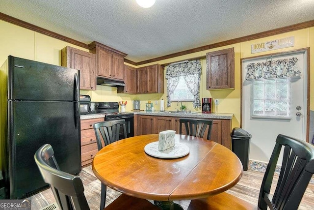 kitchen featuring a textured ceiling, black appliances, ornamental molding, and light hardwood / wood-style floors