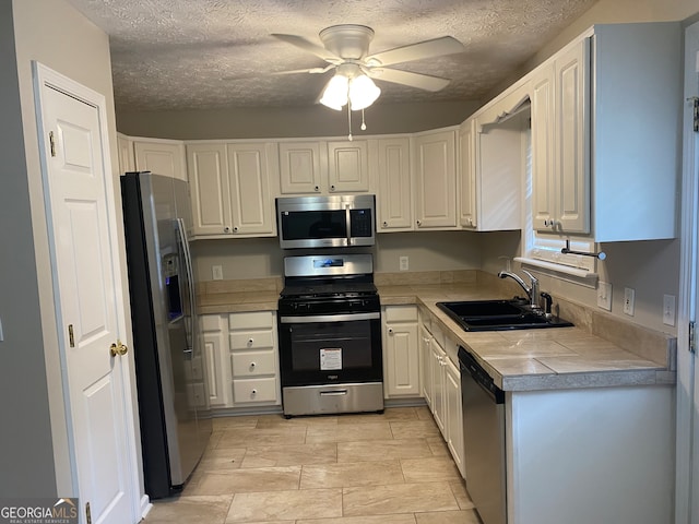 kitchen featuring appliances with stainless steel finishes, a textured ceiling, sink, and ceiling fan