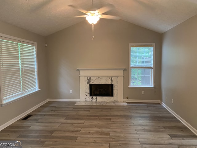 unfurnished living room featuring a textured ceiling, a fireplace, hardwood / wood-style floors, lofted ceiling, and ceiling fan