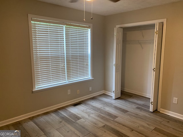 unfurnished bedroom with a closet, light wood-type flooring, and multiple windows