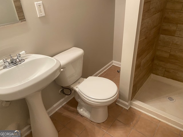 bathroom with tile patterned flooring, toilet, and a tile shower