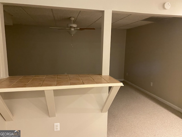 interior space featuring carpet flooring, ceiling fan, and a drop ceiling