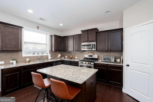 kitchen featuring appliances with stainless steel finishes, backsplash, a center island, and dark hardwood / wood-style floors