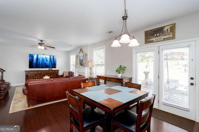 dining area with dark wood-type flooring and ceiling fan with notable chandelier