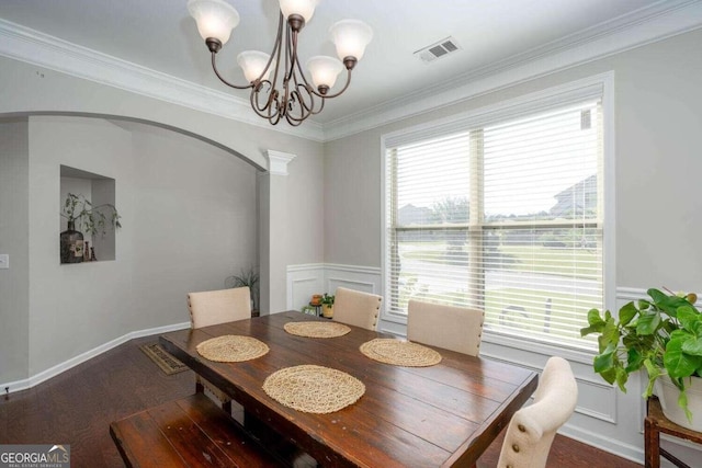 dining area featuring dark wood-type flooring, ornamental molding, and a notable chandelier