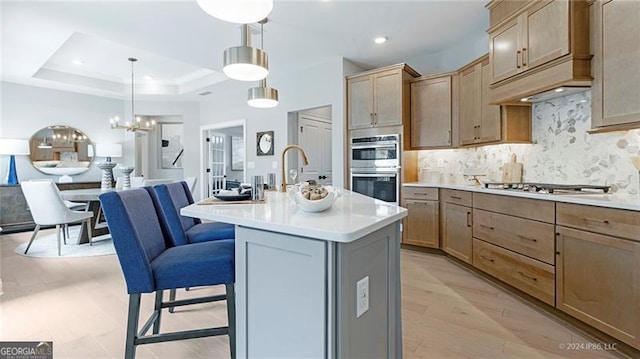 kitchen with a kitchen island with sink, a notable chandelier, a kitchen bar, decorative light fixtures, and appliances with stainless steel finishes