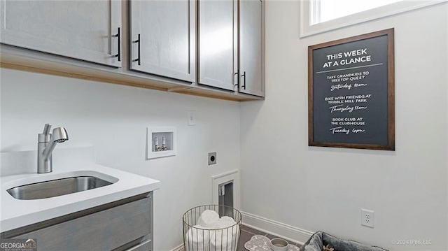 laundry area with hookup for a washing machine, electric dryer hookup, cabinets, and sink