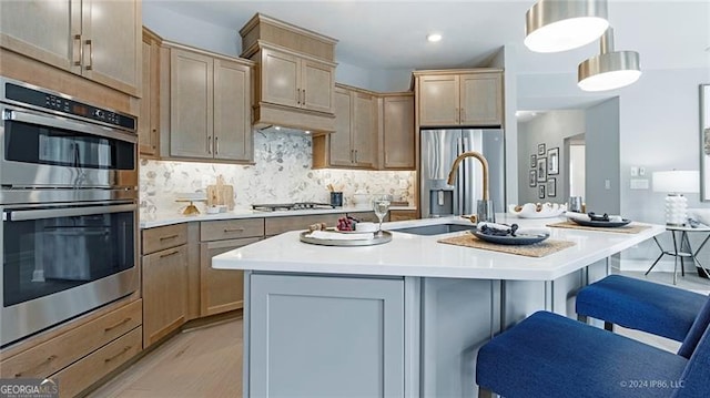 kitchen featuring decorative light fixtures, a breakfast bar area, stainless steel appliances, and a kitchen island with sink