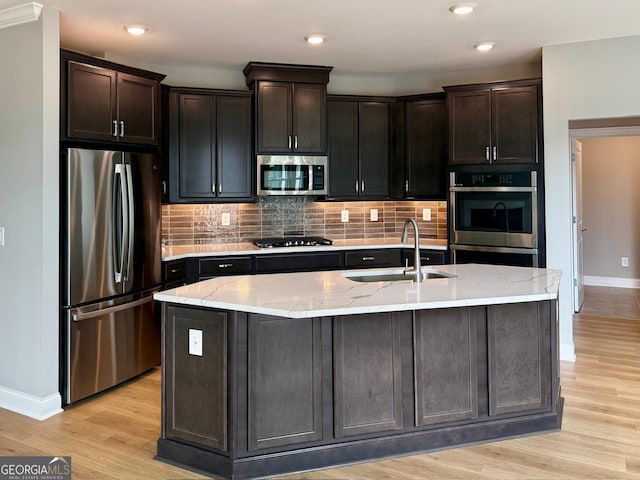 kitchen with backsplash, light wood-style flooring, stainless steel appliances, and a sink