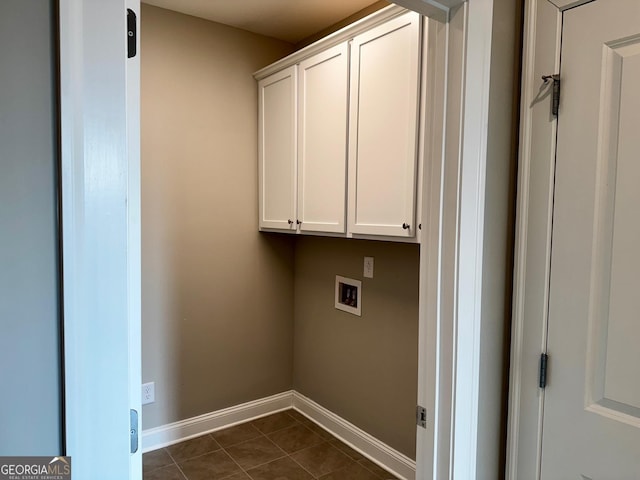 laundry area featuring dark tile patterned floors, baseboards, cabinet space, and hookup for a washing machine