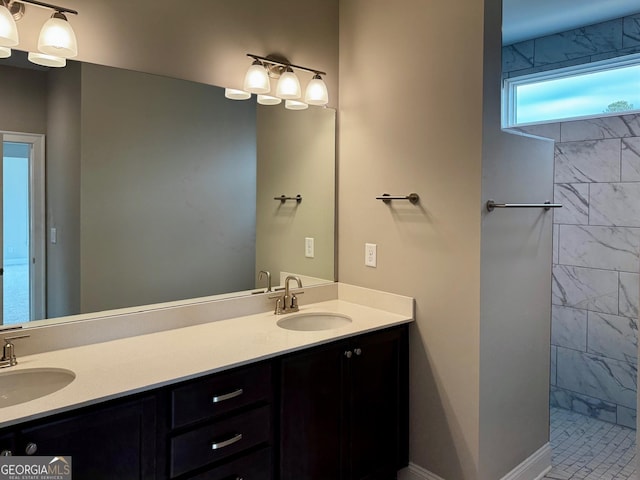 full bath featuring double vanity, a tile shower, and a sink