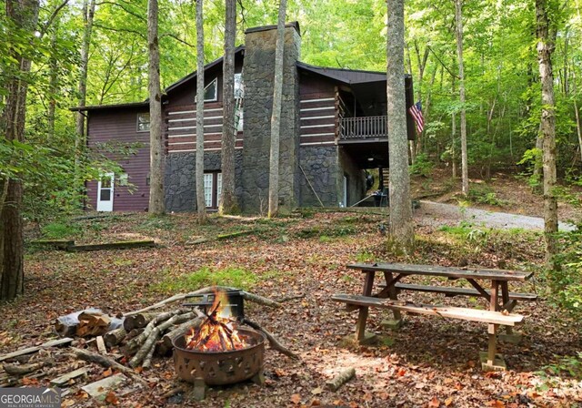 view of property exterior featuring an outdoor fire pit and a balcony