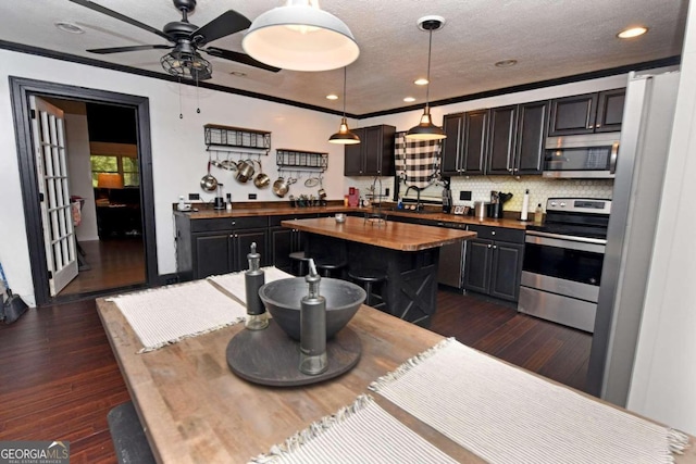 kitchen featuring decorative light fixtures, stainless steel appliances, dark wood-type flooring, ceiling fan, and butcher block counters