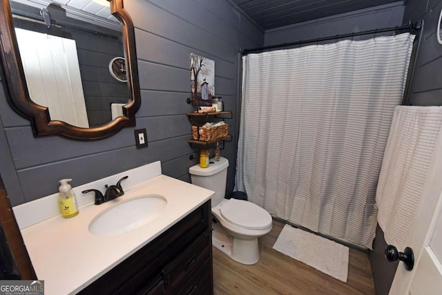 bathroom with toilet, wooden walls, vanity, curtained shower, and hardwood / wood-style flooring