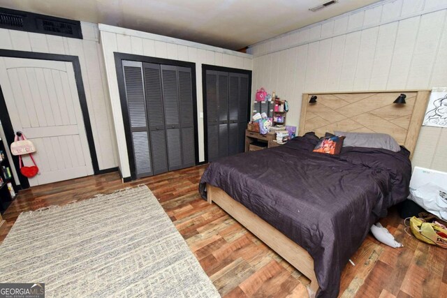 bedroom featuring hardwood / wood-style floors and two closets