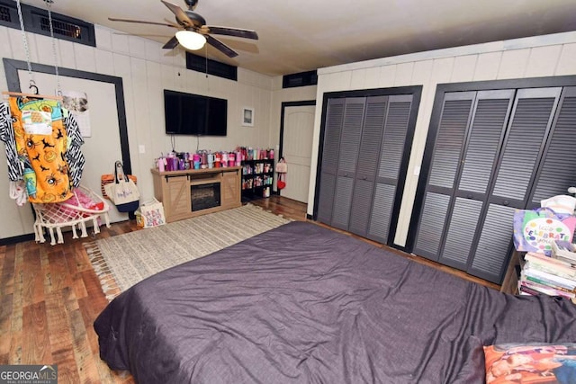 bedroom featuring hardwood / wood-style flooring, two closets, and ceiling fan