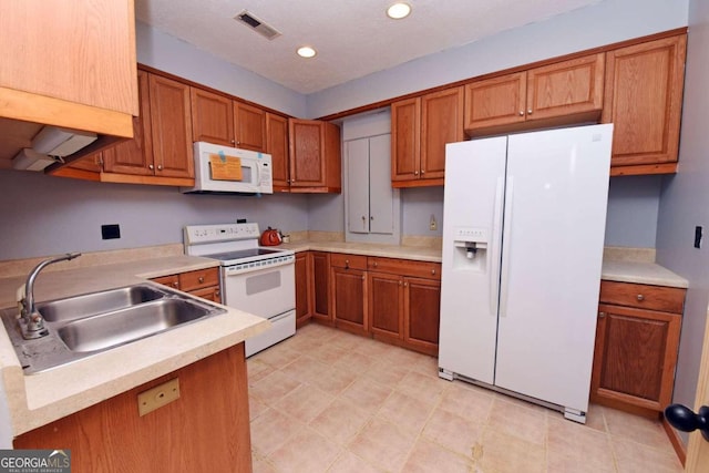 kitchen featuring white appliances, kitchen peninsula, and sink