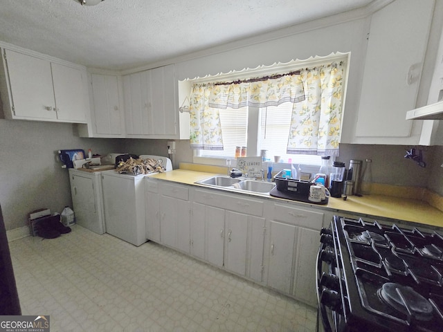 kitchen featuring black gas stove, separate washer and dryer, light countertops, and a sink