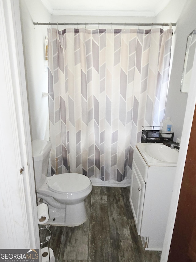 bathroom featuring toilet, ornamental molding, a shower with curtain, wood finished floors, and vanity