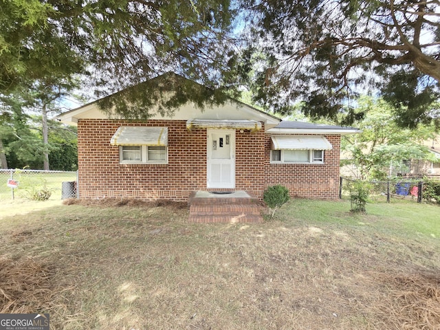 bungalow-style house with brick siding, a front lawn, and fence