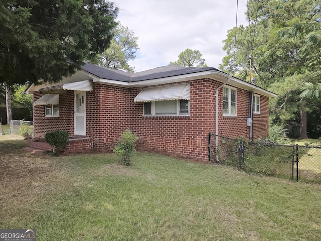 view of front of house with brick siding, a gate, a front yard, and fence