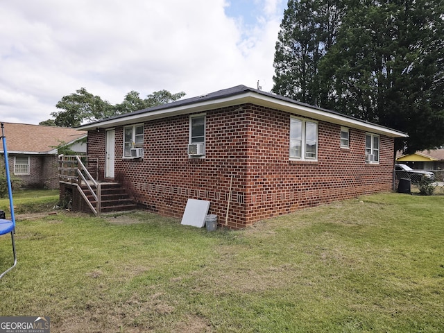 view of property exterior with cooling unit, a trampoline, brick siding, and a lawn