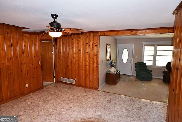 foyer featuring ceiling fan and wood walls