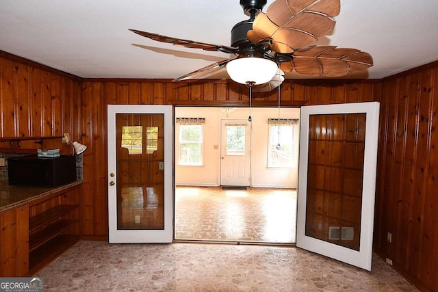 foyer with crown molding, ceiling fan, and wooden walls