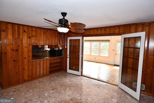 interior space with wood walls, ceiling fan, ornamental molding, and sink