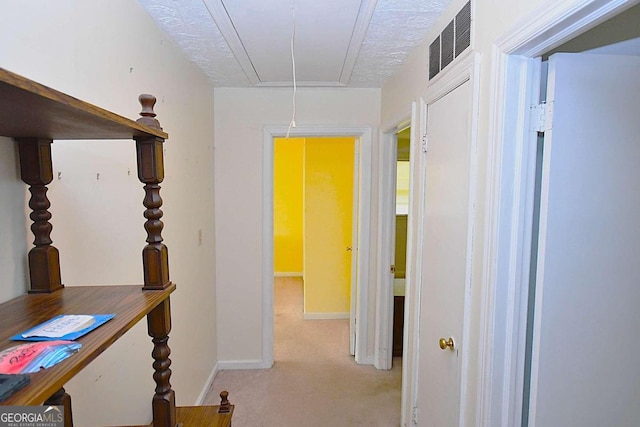 corridor with light carpet and a textured ceiling