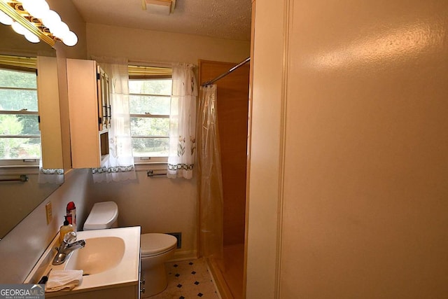 bathroom with a textured ceiling, vanity, toilet, and walk in shower