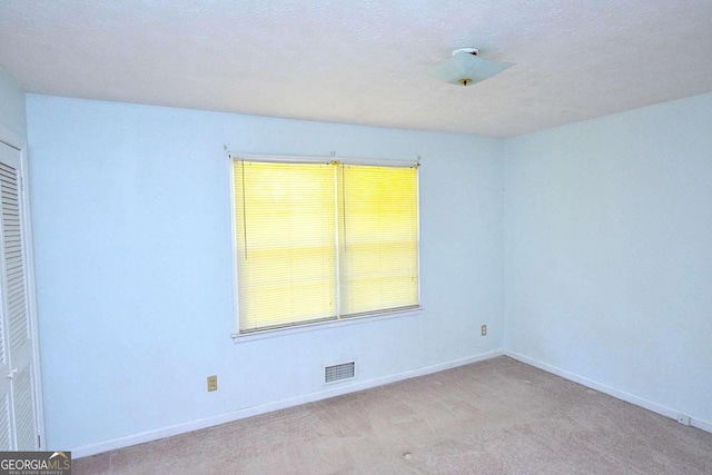 carpeted spare room featuring a textured ceiling