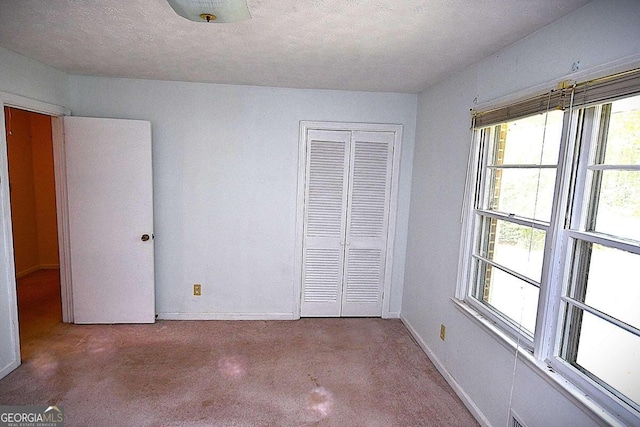 unfurnished bedroom with multiple windows, a closet, and a textured ceiling