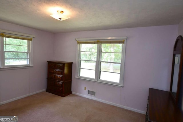 unfurnished bedroom featuring light carpet and a textured ceiling