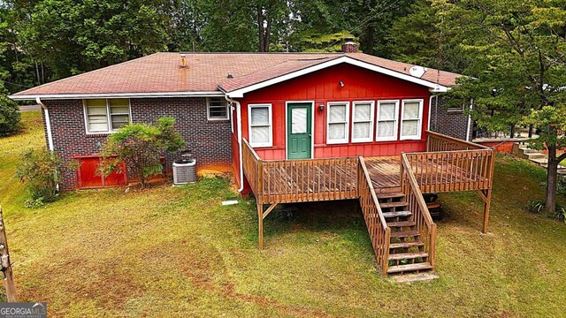 rear view of house with central AC, a wooden deck, and a yard