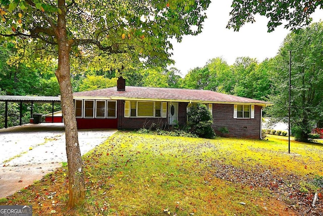 ranch-style house featuring covered porch, a carport, and a front lawn