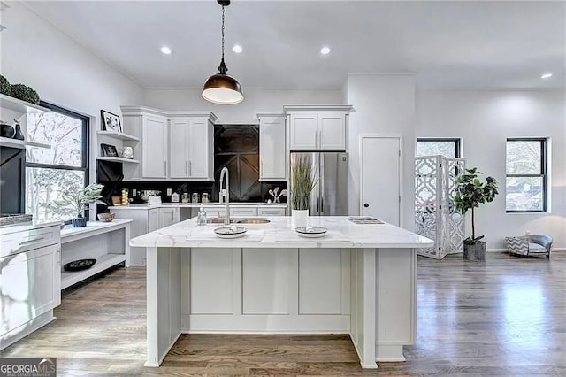 kitchen with pendant lighting, white cabinetry, light stone countertops, and stainless steel fridge