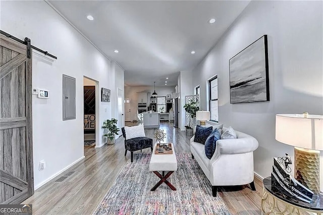 living room featuring a barn door, light wood-type flooring, and electric panel