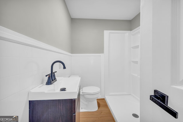 bathroom with toilet, a shower, tile walls, wood-type flooring, and vanity