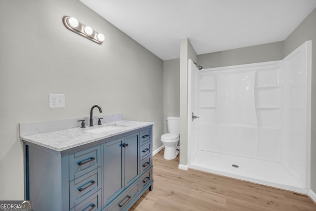 bathroom with hardwood / wood-style floors, walk in shower, toilet, and vanity