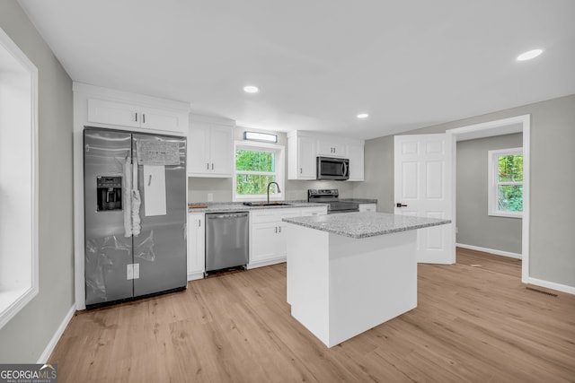 kitchen featuring a healthy amount of sunlight, light hardwood / wood-style flooring, stainless steel appliances, sink, and white cabinets