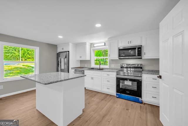 kitchen with appliances with stainless steel finishes, sink, white cabinetry, and a healthy amount of sunlight